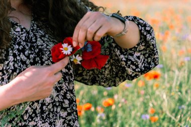 Haşhaş, papatya ve çiçek çelengi ören kadınların yakın çekimi..