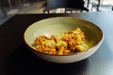 Kızarmış mantarlar haşlanmış patatesler, yeşil otlar, maydanoz ve dereotlar öğle yemeği için bir kasede..