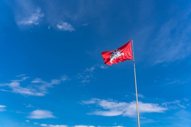 Litvanya 'nın arması. Kırmızı arka planda at üstünde kılıcı olan bir binici. Mavi gökyüzüne karşı Litvanya 'nın tarihi bayrağı.