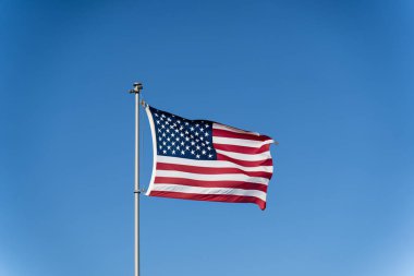 Amerika Birleşik Devletleri bayrağı açık mavi gökyüzüne karşı rüzgarda dalgalanıyor. ABD bayrağı sallıyor.
