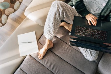 Top view of a woman in pajamas with laptop and notepad. clipart