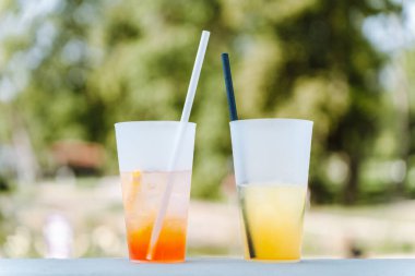 Parktaki bir yazlık kafenin masasında farklı yaz tazeleyici kokteyller olan iki bardak. Aperol şırıngası ve limonata.