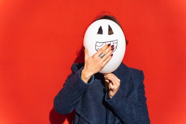 Elinde balon tutan ve ağzı kırmızı arka planda olan bir kadın..