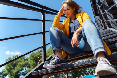 Rahatlamış bir kadın güneşli bir günde dışarıda oturuyor..