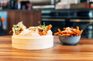 Lokantada yumuşak bao çörekleri ve patates kızartması olan bambu tenceresi..