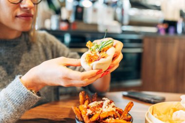 Modern bir kafe ortamında gurme çöreğin tadını çıkaran bir kadın..