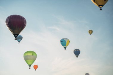 Festival sırasında mavi gökyüzünde uçan bir grup renkli sıcak hava balonu..