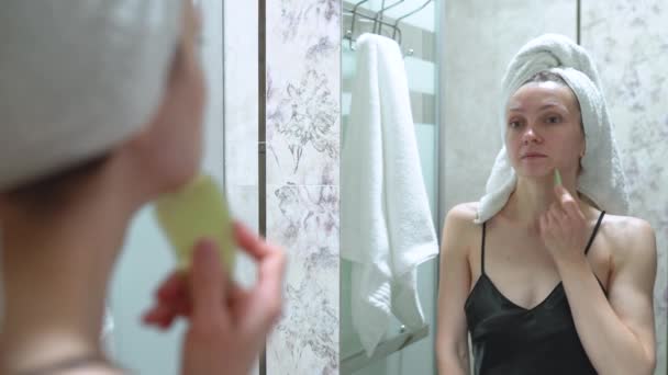 Una Donna Massaggio Facciale Con Raschietto Guazzo Guarda Allo Specchio — Video Stock