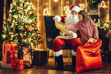 Noel Baba ve küçük kız yardımcısı dilek listesindeki tüm hediyelerin çuvallayıp çuvallamadığını kontrol ediyor. Noel zamanı. Yeni yıl konsepti 
