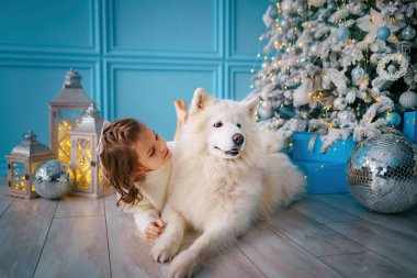  Yılbaşı ağacı konseptinin yanında yatarken küçük bir kız hasta bir köpeği okşuyor. Noel süslemeleri 