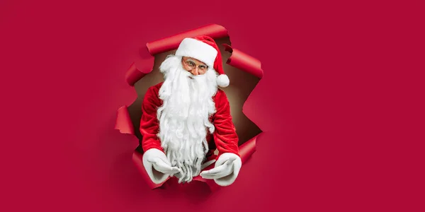 Papai Noel Espreitando Através Buraco Papel Vermelho Enquanto Gesticula Mãos — Fotografia de Stock