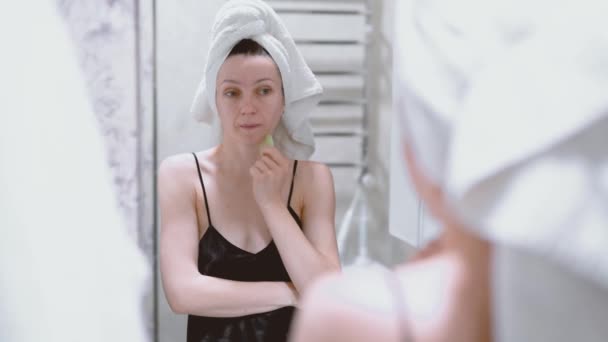 Frau Macht Gesichtsmassage Mit Einem Gouachekratzer Und Schaut Den Spiegel — Stockvideo