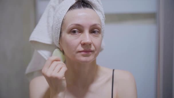 Una Donna Massaggio Facciale Con Raschietto Guazzo Guarda Allo Specchio — Video Stock