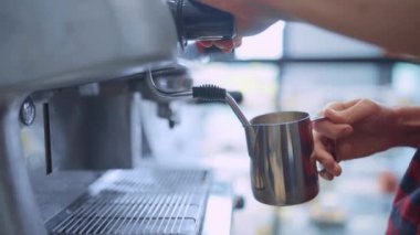  Barista bir kafede kahve makinesini kullanarak kapuçino için süt hazırlıyor. Kahve dükkanı konsepti 