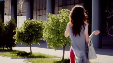 Güneş gözlüklü çekici esmer kadın, zarif giysiler içindeki bir şehre ağır çekimde gider ve arkasını döner.. 