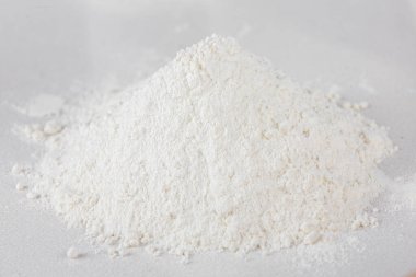 Beyaz masa üstü arka planında ellenmiş un yığını. Beyaz arka planda bir avuç beyaz un. Dağınık un. 