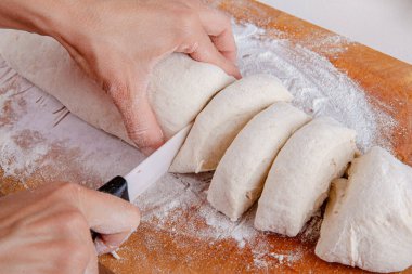 Tahtaya saplanmış hamur hamuruyla kesilmiş kadın elleri. Taze elastik hamur pişirme işlemi. Doğal ev yemekleri. Ev yapımı yemek. 