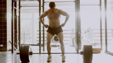 Güçlü vücut geliştirici spor salonunda büyük bir çubuk kaldırıyor. Halterci ağırlık kaldırıyor. Kas geliştirme, sıkı çalışma.