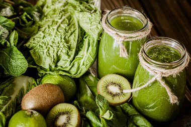 Ahşap masadaki malzemelerle karıştırılmış yeşil smoothie. Sağlıklı gıda konsepti. Yeşil kokteyl. 