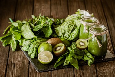 Ahşap masadaki malzemelerle karıştırılmış yeşil smoothie. Sağlıklı gıda konsepti. Yeşil kokteyl. 