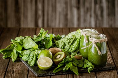 Ahşap masa seçici odak noktasındaki malzemelerle harmanlanmış yeşil smoothie. Sağlıklı gıda konsepti. Yeşil kokteyl 