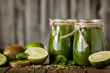 Ahşap masa seçici odak noktasındaki malzemelerle harmanlanmış yeşil smoothie. Sağlıklı gıda konsepti. Yeşil kokteyl 