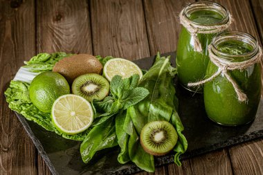 Ahşap masa seçici odak noktasındaki malzemelerle harmanlanmış yeşil smoothie. Sağlıklı gıda konsepti. Yeşil kokteyl 
