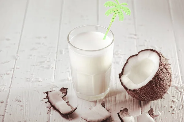 白い木製のテーブルの上にココナッツフルーツとガラスのココナッツミルク 牛乳の代替概念 熱帯飲料 — ストック写真