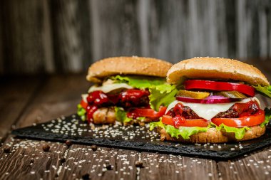 Et, peynir, domates, soğan, dolmalık biber ve marullu leziz iştah burgerleri. Seçici odak. 