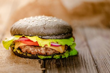  İştah açıcı hamburgerin önünde suni et ve taze yeşillik ve sebzeler ve kırsal ahşap masada peynir. Vejetaryen yemeği. Seçici odak 