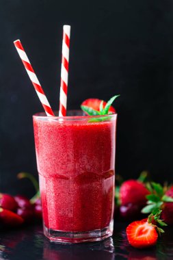 Taze çilek suyu ya da bardakta saman ve koyu arkaplanda taze çilek ve kirazlı smoothie. Seçici odaklanma. Vejetaryen yemeği. Sağlıklı yiyecekler. Vitamin yiyeceği. 