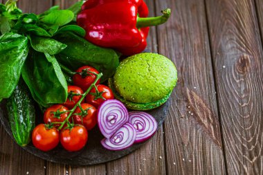 Sebzeler, yeşil çörekler ve ahşap masadaki yeşilliklerle hamburger yapma sürecinden. Vejetaryen yemeği. Vejetaryen hamburgerler 