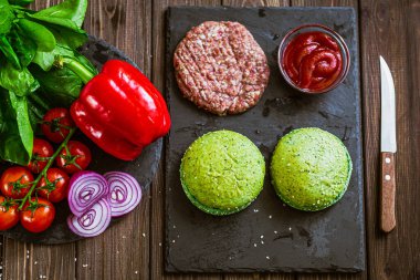 Sebzeler, yeşil çörekler ve yapay etle hamburger yapma sürecinin yukarısından. Vejetaryen yemeği. 