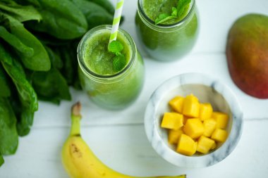 Muzlu, mangolu, ahşap masa üzerinde ıspanaklı smoothie. Sağlıklı yiyecekler. Vejetaryen diyeti. Seçici odak 