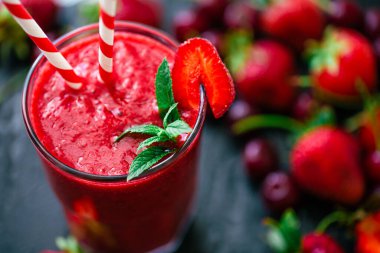 Yakın çekimde taze meyve suyu ya da bardakta saman ve koyu renkli çilek ve kirazlı smoothie. Seçici odaklanma. Vejetaryen yemeği. Sağlıklı yiyecekler. Vitamin yiyeceği. 
