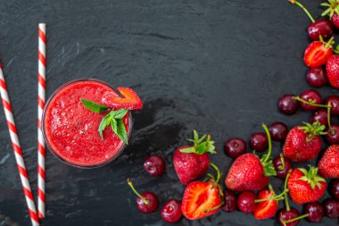 Yukardan taze çilek suyu ya da bardakta saman, taze çilek ve siyah kirazlı smoothie. Vejetaryen yemeği. Sağlıklı yiyecekler. Vitamin yiyeceği. 