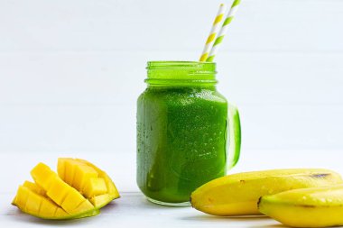 Muzlu smoothie, mango, ahşap beyaz masada ıspanak. Sağlıklı yiyecekler. Vejetaryen diyeti. Seçici odak 