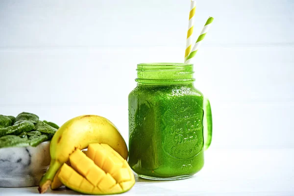 Front view of smoothie with banana, mango, spinach on wooden white table. Healthy food. Vegetarian diet. Selective focus
