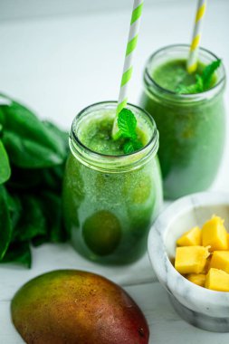 Mangolu yeşil smoothie, ahşap beyaz masada ıspanak. Sağlıklı yiyecekler. Vejetaryen diyeti. Seçici odak 