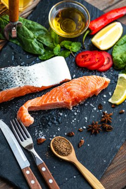 Çiğ somon balığı fileto, limon, ıspanak, baharat, zeytin yağı, kırmızı biber tahtada pişirmeye hazır. Ev yapımı yemek. Seçici odak 