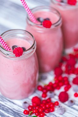 Three jars of yogurt smoothie with cranberries, raspberries and blueberries standing on table. Fruit dessert. Berry smoothie. healthy dieting concept. Selective Focus . Vertical 
