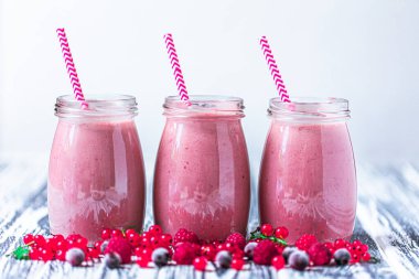 Front view of three jars of yogurt smoothie with cranberries, raspberries and blueberries standing on wooden table. Fruit dessert. Berry smoothie. healthy dieting concept. Selective Focus 