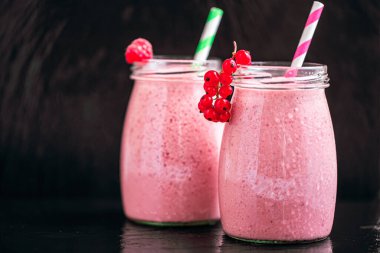 Front view of two jars of yogurt smoothie with cranberries, raspberries standing on black background. Fruit dessert. Berry smoothie. healthy dieting concept. Selective Focus 