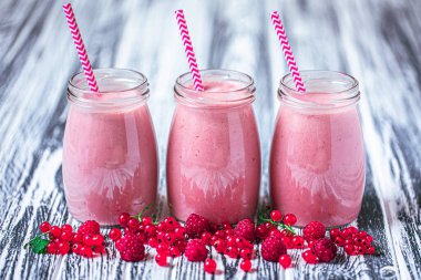 Front view of three jars of yogurt smoothie with cranberries, raspberries standing on wooden table. Fruit dessert. Berry smoothie. healthy dieting concept. Selective Focus 