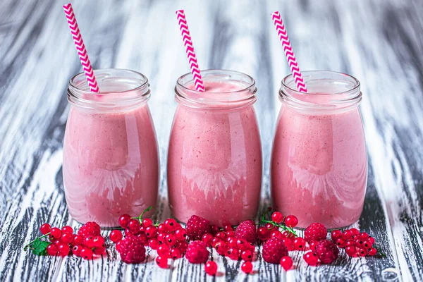 Front view of three jars of yogurt smoothie with cranberries, raspberries standing on wooden table. Fruit dessert. Berry smoothie. healthy dieting concept. Selective Focus