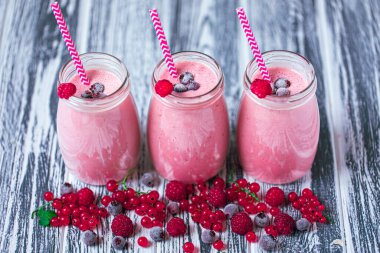 Three jars of yogurt smoothie with cranberries, raspberries and blueberries standing on table. Fruit dessert. Berry smoothie. healthy dieting concept. Selective Focus 