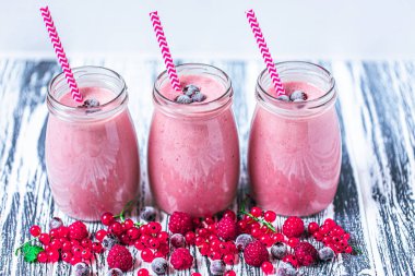 Side view of several jars of yogurt smoothie with cranberries, raspberries and blueberries standing on wooden table. Fruit dessert. Berry smoothie. healthy dieting concept. Selective Focus 