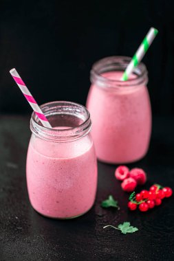 From above view of two jars of yogurt smoothie with cranberries, raspberries standing on black table. Fruit dessert. Berry smoothie. healthy dieting concept. Selective Focus 