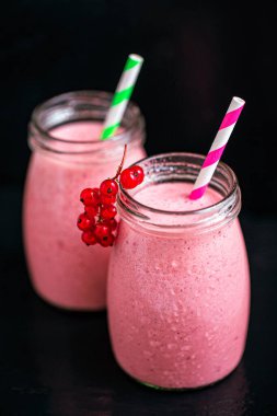 Side view of two jars of yogurt pink smoothie with berries on black background. Fruit dessert. Berry smoothie. healthy dieting concept. Selective Focus 