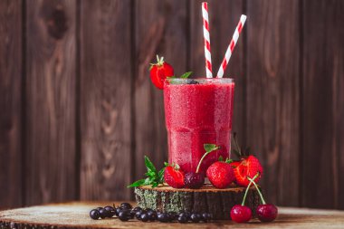 Composition of glass with fresh crimson smoothie with summer berries on wooden table. Healthy eating concept. Vitamin food. Selective focus 